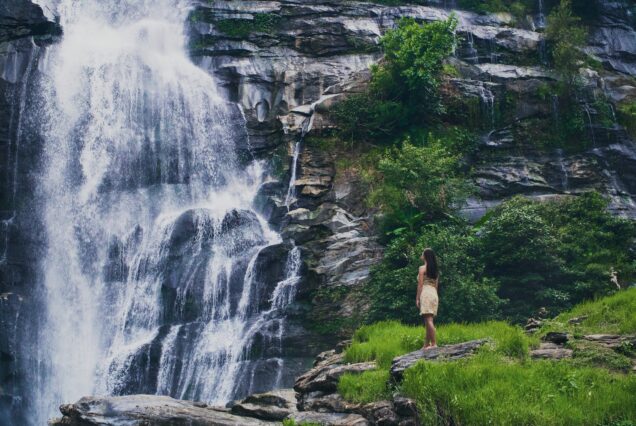 A fascinating low angle shot of a female admiring the waterfall in Doi Inthanon park in Thailand